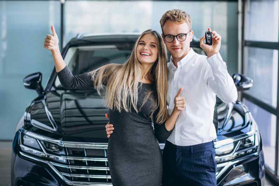 A happy couple with their insured car